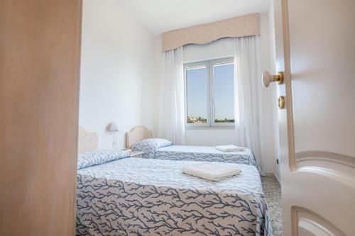 two beds in a room with a window at Hotel Poseidon in Diamante