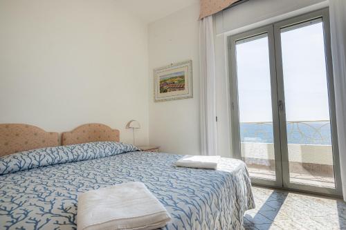 a bedroom with a bed and a large window at Hotel Poseidon in Diamante