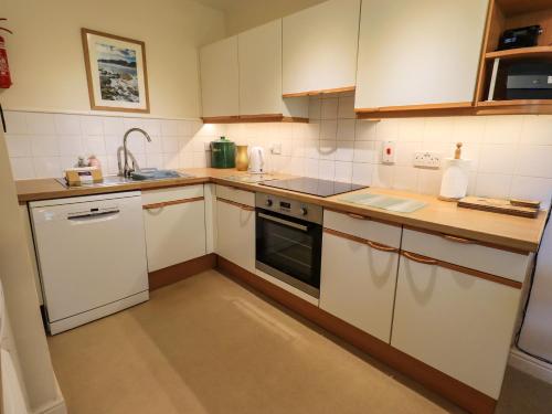 a small kitchen with white cabinets and a sink at Puddleduck in Ambleside