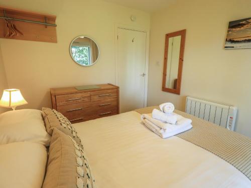 a bedroom with a bed with towels and a mirror at Puddleduck in Ambleside