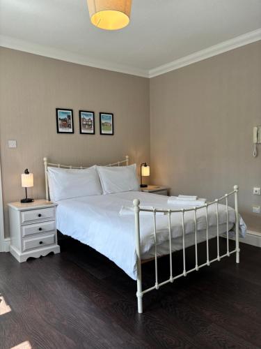 ein Schlafzimmer mit einem weißen Bett mit zwei Tischen und zwei Lampen in der Unterkunft Large East Side Room above G Grace & Son in Tring