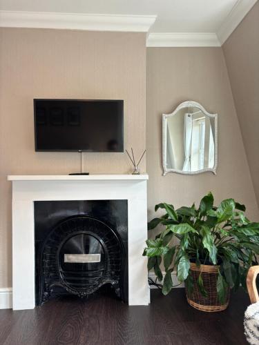 a living room with a fireplace with a tv above it at Large East Side Room above G Grace & Son in Tring