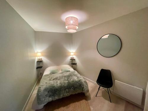 une chambre avec un lit, un miroir et une chaise dans l'établissement « La Bicyclette » 35m2 tout équipé centre ville, à Mayenne