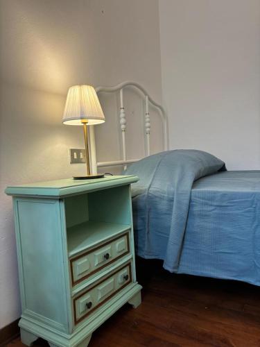 a blue nightstand with a lamp on it next to a bed at Villa del Monte di Cocco in Massarosa