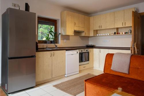 a kitchen with wooden cabinets and a stainless steel refrigerator at Dunakavics vendégház stranddal in Zebegény