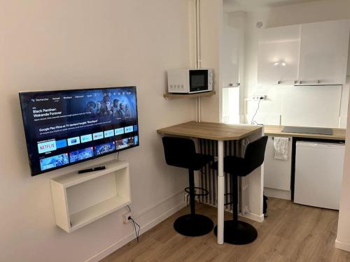 Il comprend une cuisine avec une table et une télévision murale. dans l'établissement Studio Occitanie-Hopitaux-Facultés & Parking gratuit, à Montpellier