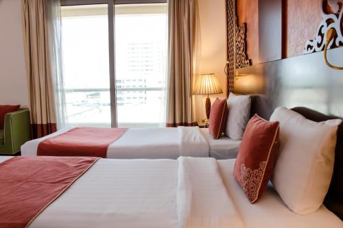 a hotel room with two beds and a window at Dubai Grand Hotel by Fortune, Dubai Airport in Dubai