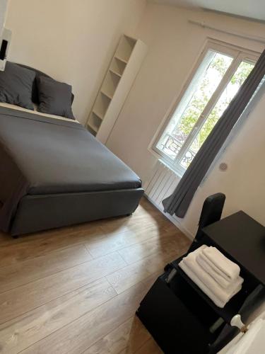 1 dormitorio con cama, escritorio y ventana en Appartement insulaire proche Paris, en LʼÎle-Saint-Denis