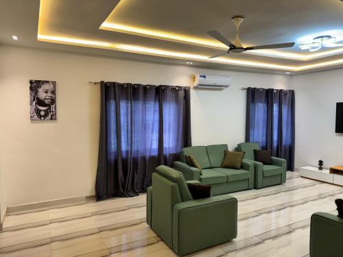 una sala de espera con sillas verdes y techo en Private Apartments in a Home, en Ejisu