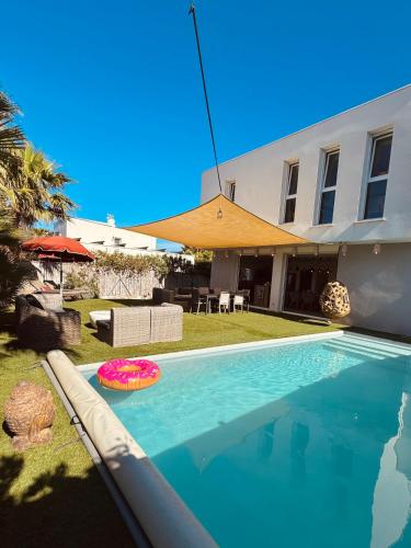 - une piscine avec un frisbee en face d'une maison dans l'établissement Villa proche plage mer, piscine grand terrain Capao Hotel, au Cap d'Agde