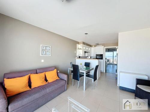 un salon avec un canapé et une table et une cuisine dans l'établissement Horizon Sérénité Vue Mer, 2e Étage Confort, à Bray-Dunes