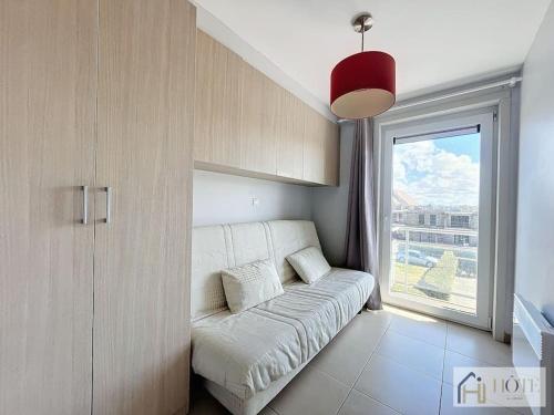 - un canapé blanc dans une chambre avec fenêtre dans l'établissement Horizon Sérénité Vue Mer, 2e Étage Confort, à Bray-Dunes