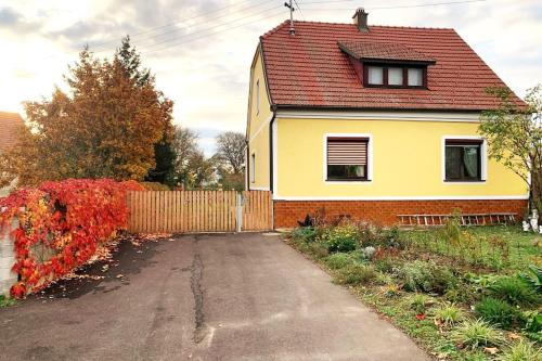 a yellow house with a red roof and a driveway at Ferienhaus mit Garten in Thermennähe in Strebersdorf