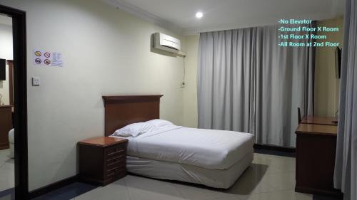 Dormitorio pequeño con cama y espejo en The Upper Deck Hotel, en Kudat