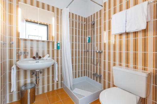 a bathroom with a toilet and a sink at Parkhotel Brenscino Brissago in Brissago