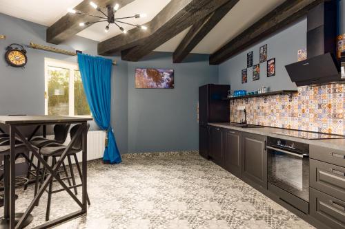 a kitchen with blue walls and a counter with a table at Karlovy Charme Inn by Rentez in Karlovy Vary