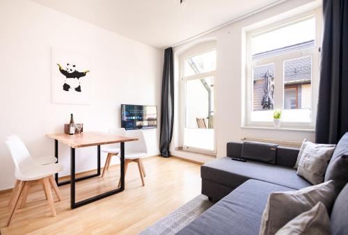 ein Wohnzimmer mit einem Sofa und einem Tisch in der Unterkunft Ko-Living - Händel Stuben - Street Art Design Apartments - Altstadt - zentral - Küche - Smart TV - mehrere Apartments - bis zu 6 P in Halle an der Saale