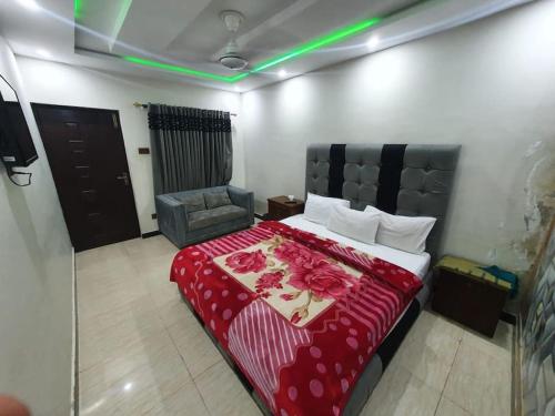 um quarto com uma cama com um cobertor vermelho e uma cadeira em Stunning Apartment/Guest House em Islamabad