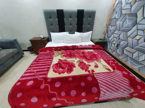 uma cama com um cobertor vermelho com flores em Stunning Apartment/Guest House em Islamabad