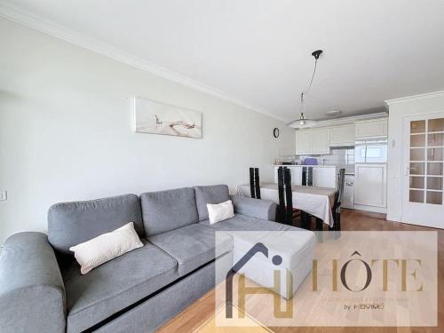 un salon avec un canapé et une cuisine dans l'établissement Horizon Marin - Vue Mer & Confort au 4e Étage, à Bray-Dunes