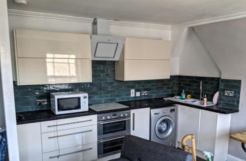 eine Küche mit weißen Schränken und einer Mikrowelle in der Unterkunft Folka Rocks in Folkestone