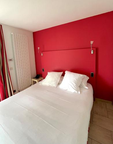 a bedroom with a white bed with a red wall at Les Maritonnes Parc & Vignoble in Romanèche-Thorins