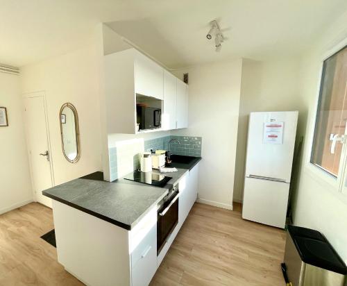 a kitchen with white cabinets and a white refrigerator at 2 pièces lumineux aux portes de Paris in Clamart