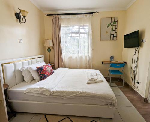 a bedroom with a bed and a desk and a window at DB Space in Nairobi