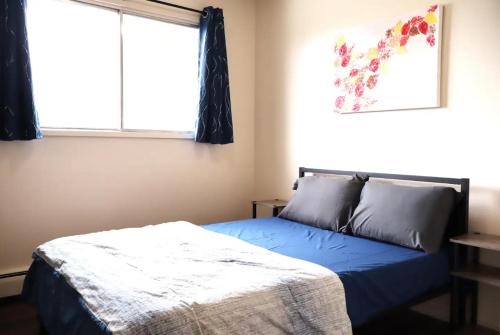 a bedroom with a blue bed and a window at Cozy Stays in Edmonton