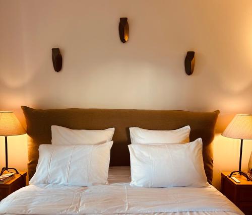1 dormitorio con 1 cama con almohadas blancas y 2 lámparas en l'Alceste, en La Ciotat