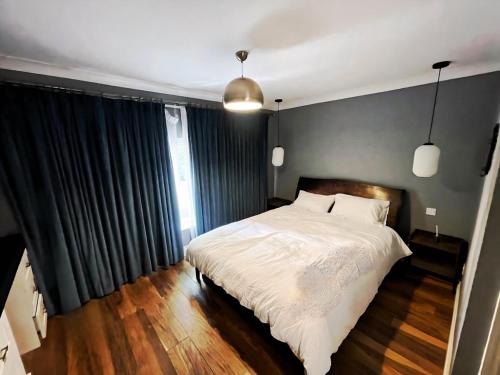 a bedroom with a large white bed with black curtains at Stylish Rental House SE16 in London