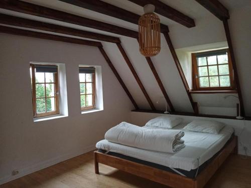 ein Schlafzimmer mit einem Bett in einem Zimmer mit Fenstern in der Unterkunft Petit gîte du Manoir de Keryvoas in Kerlouan