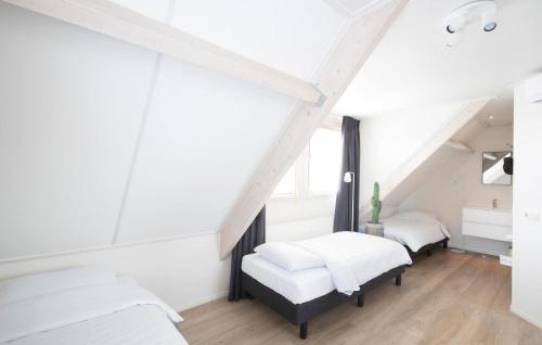 Habitación con 2 camas, paredes blancas y suelo de madera. en Het Rivierhuis en Maurik