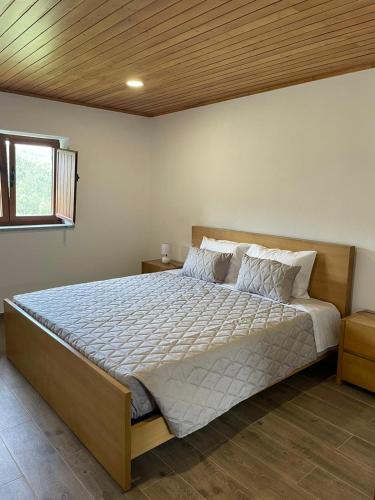 a bedroom with a large bed with a wooden ceiling at Quinta da Recochina in Castro Daire