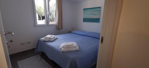 a bedroom with a blue bed with towels on it at Casa Mariposa Porto Rotondo in Rudalza