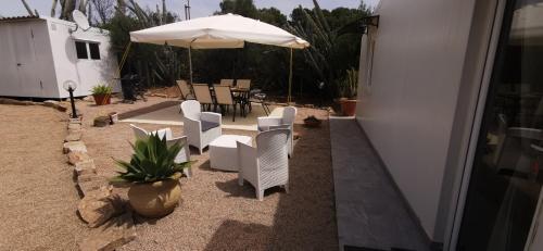 a patio with white chairs and an umbrella at Casa Mariposa Porto Rotondo in Rudalza