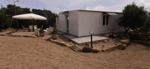 a small white house with an umbrella in a yard at Casa Mariposa Porto Rotondo in Rudalza