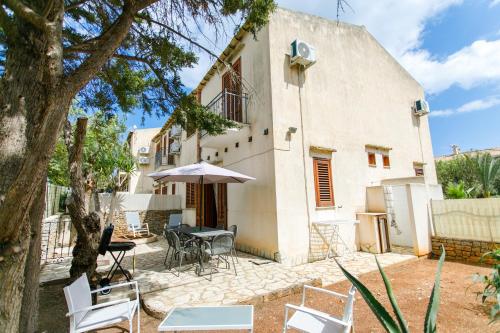 un patio con mesa, sillas y sombrilla en SanVitoTour- Residence Il Baglio en San Vito lo Capo