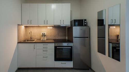 a kitchen with white cabinets and a stainless steel refrigerator at Spirit apartments Brno, with parking in Brno