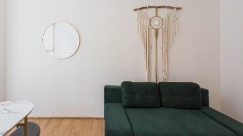 a living room with a green couch and a mirror at Spirit apartments Brno, with parking in Brno