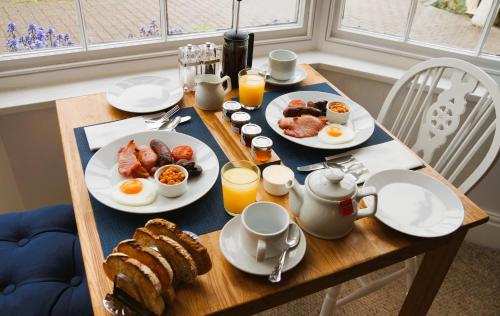 a breakfast table with eggs and bread and orange juice at Radcliffe Guest House in Ross on Wye