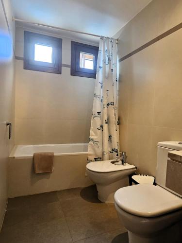 a bathroom with a toilet and a sink and a tub at Duplex Noray vista a la piscina in Puerto Calero