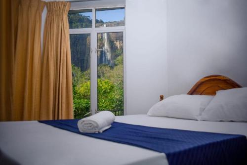 Schlafzimmer mit einem Bett und einem Fenster mit Aussicht in der Unterkunft Diyaluma Falls Inn in Koslanda