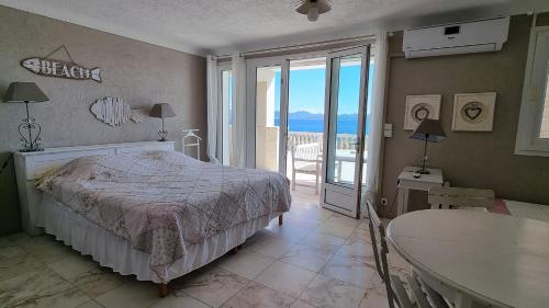 a bedroom with a bed and a table and a balcony at 83PANO Panoramamer in Les Issambres