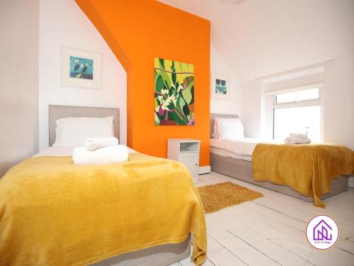 2 camas en una habitación con pared de color naranja en Victoria House,5 Bed, Fantastic Location, Free Parking, Contractors en Cardiff