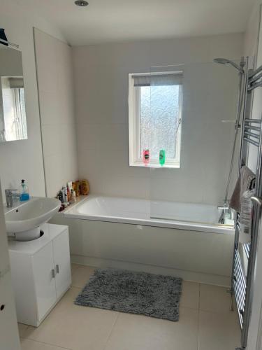 Baño blanco con bañera y lavamanos en Lovely, large double bedroom with park view, breakfast, en Hazel Grove