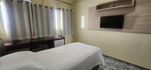 - une chambre avec un lit, un bureau et une télévision dans l'établissement Hotel das Palmeiras, à Serra Talhada