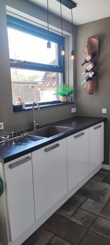 a kitchen with white cabinets and a sink and a window at La Bohème in Nijeberkoop