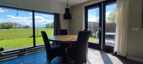 een eetkamer met een tafel en stoelen en een groot raam bij La Bohème in Nijeberkoop