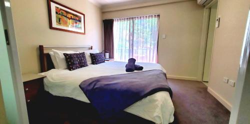 un dormitorio con una cama con un osito de peluche sentado en ella en Cbd Perth A Gem 1bedroom Apartment, en Perth